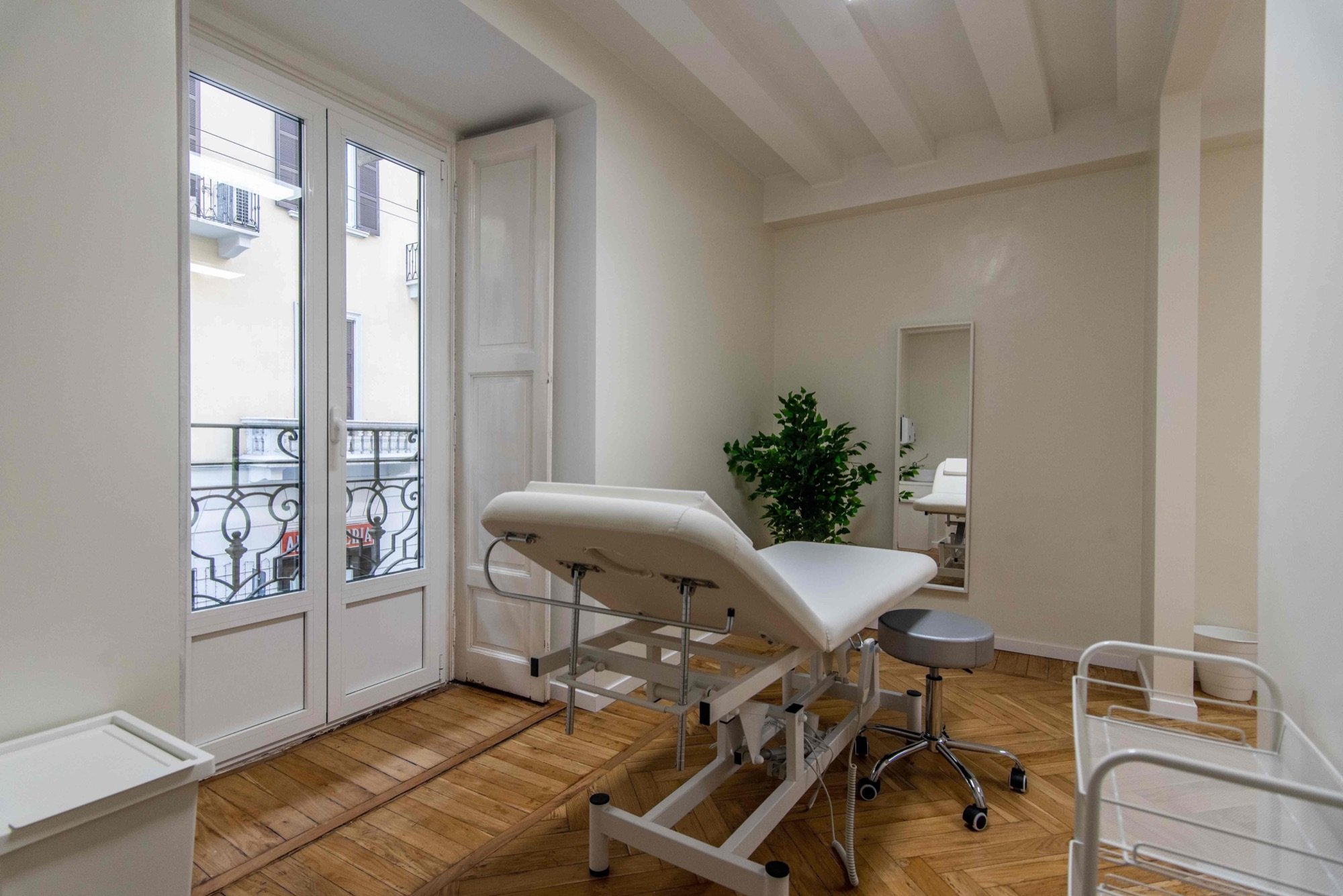 Lettino da visita vicino alle portefinestre in ambulatorio medico Exclusive presso Spatium Brera, Milano