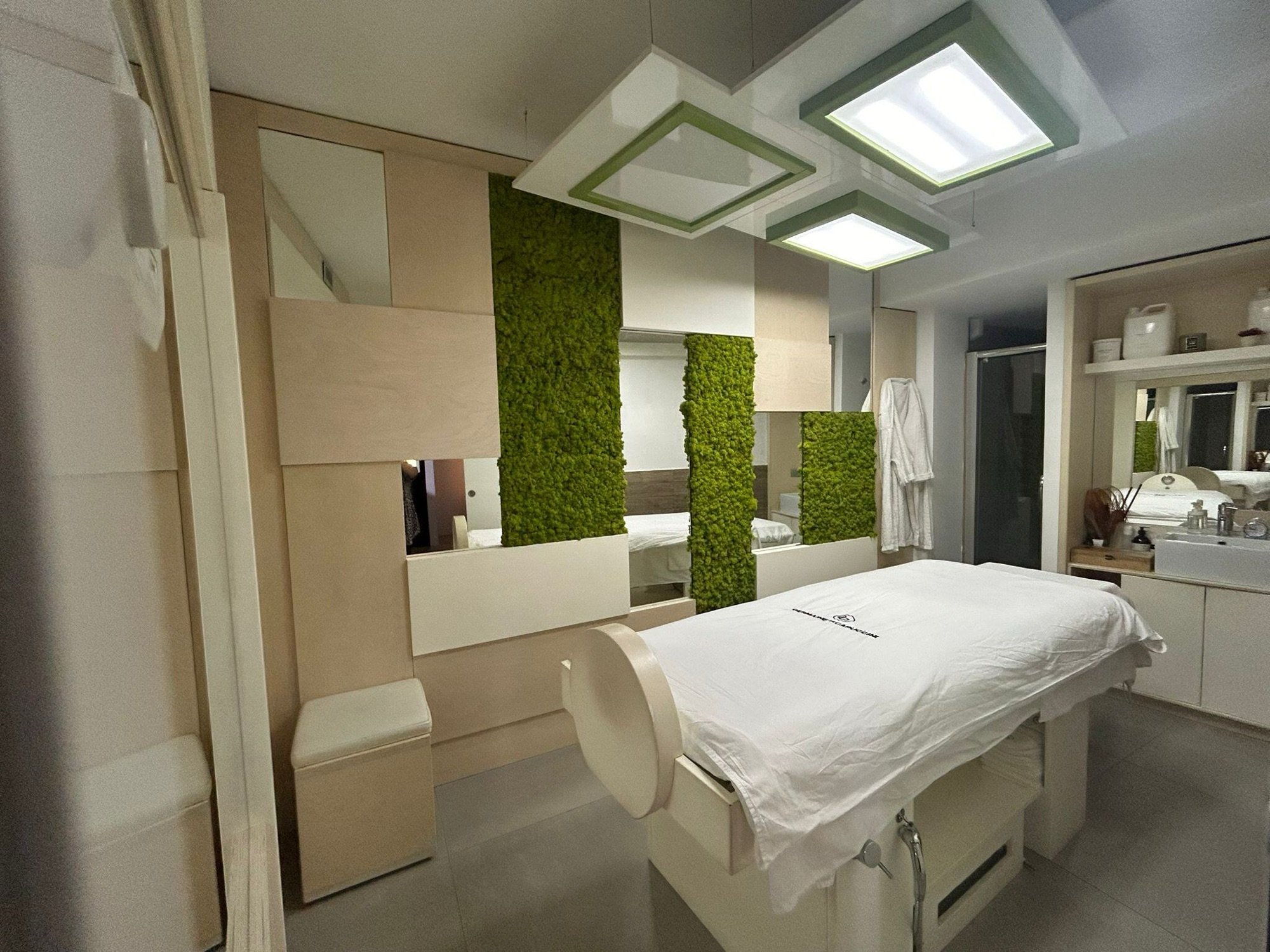 Lettino trattamenti in ambiente estetico con pareti verdi decorative in studio estetico presso Spatium Garibaldi, Salerno