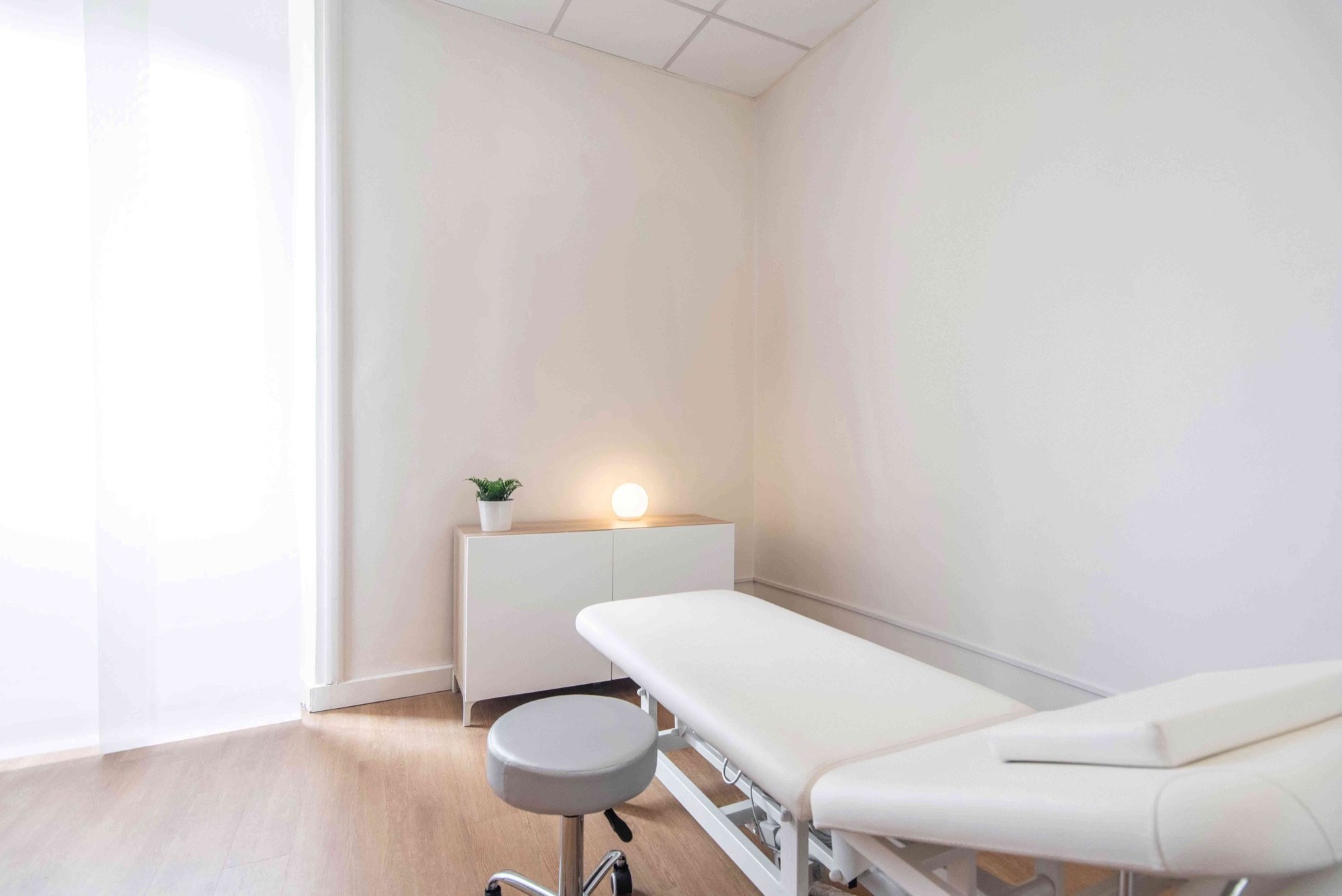 Lettino da visita con sgabello e mobile illuminato in studio medico Lounge presso Spatium Parioli, Roma