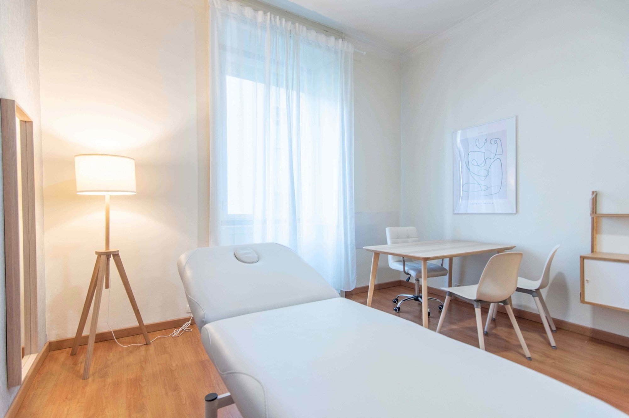 Lettino da visita in primo piano con tavolo e sedute in studio olistico Exclusive presso Spatium Caiazzo, Milano