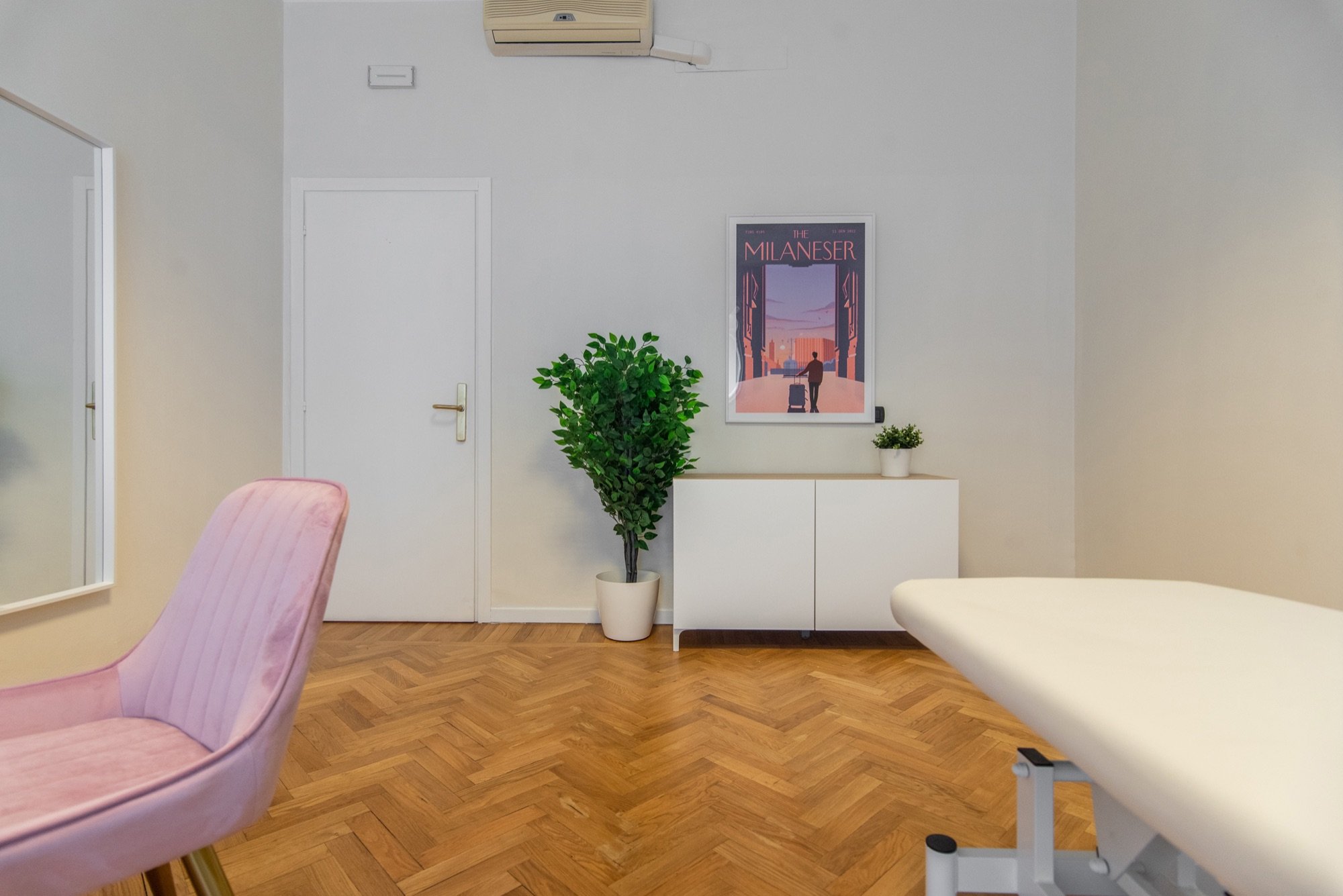 Lettino da visita con poltroncina rosa, pianta e mobile in studio olistico Lounge presso Spatium Santa Sofia, Milano