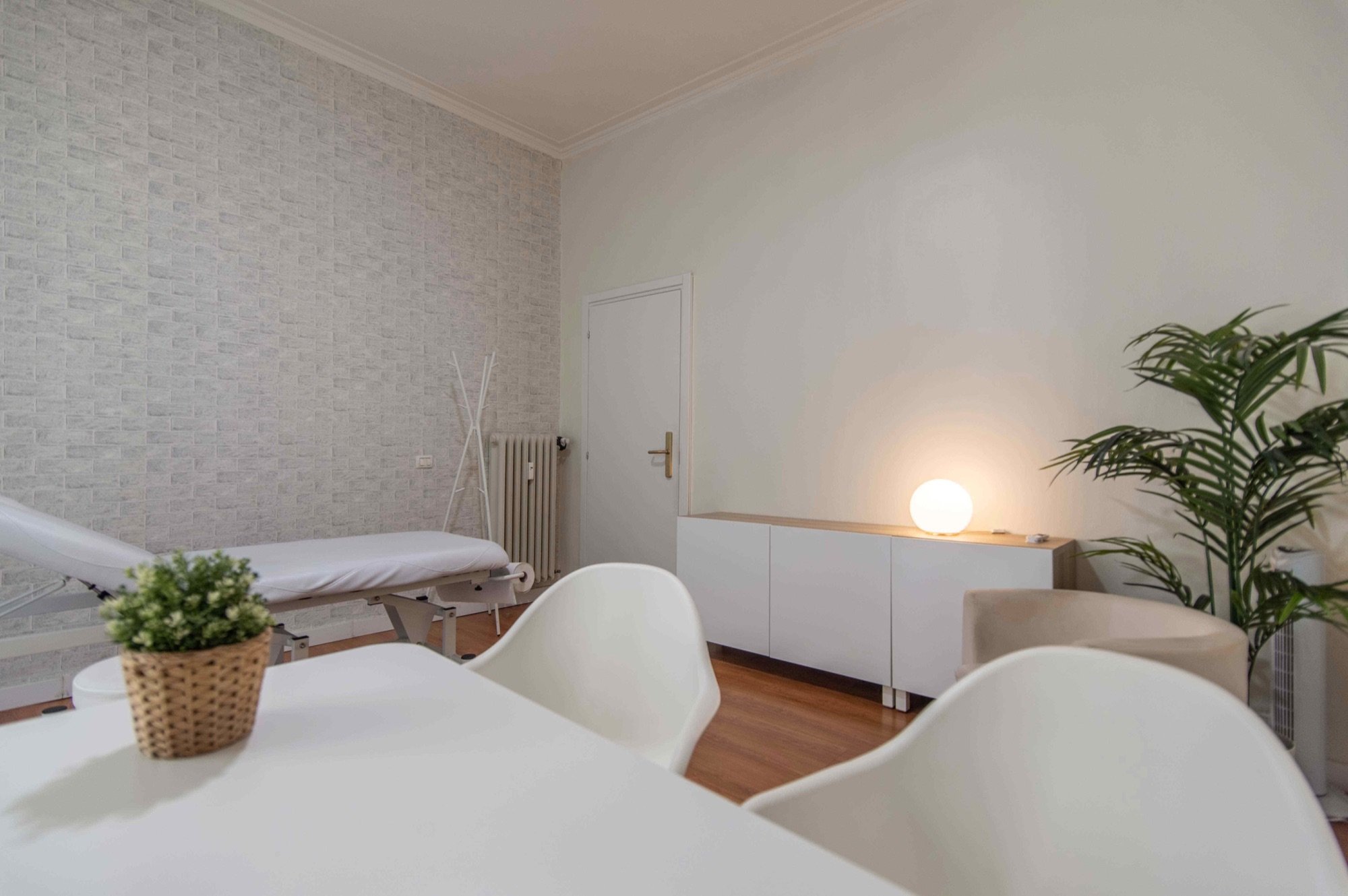 Tavolo con sedute e lettino sullo sfondo in studio olistico Exclusive presso Spatium Caiazzo, Milano