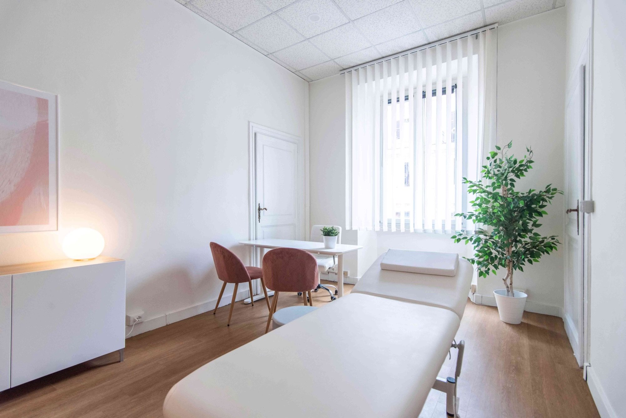 Lettino da visita con tavolo, sedute rosa e pianta in studio olistico Top presso Spatium Parioli, Roma