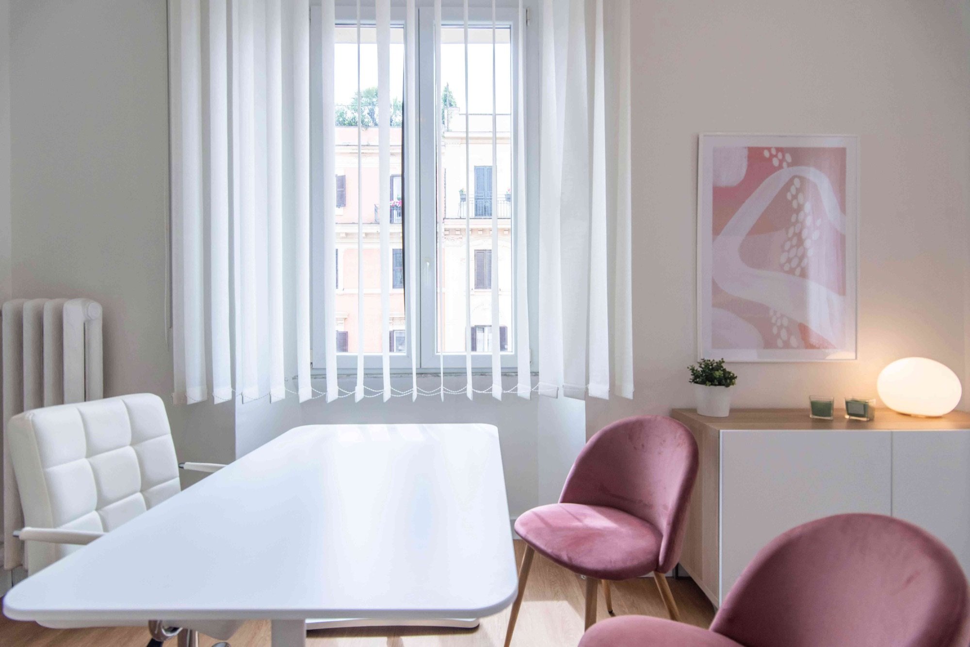 Tavolo colloquio con sedute rosa e lampada vicino alla finestra in studio olistico Exclusive presso Spatium Parioli, Roma
