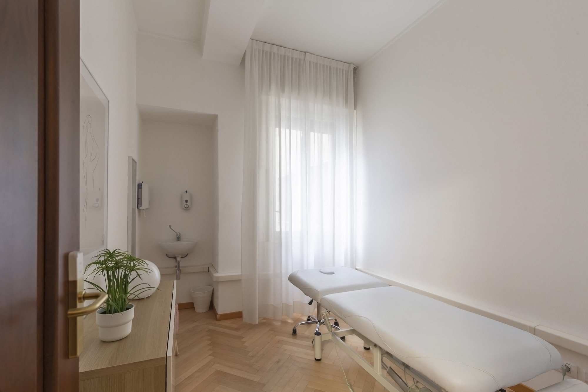 Lettino da visita vicino alla finestra con lavabo in studio professionale Standard presso Spatium Duomo, Milano