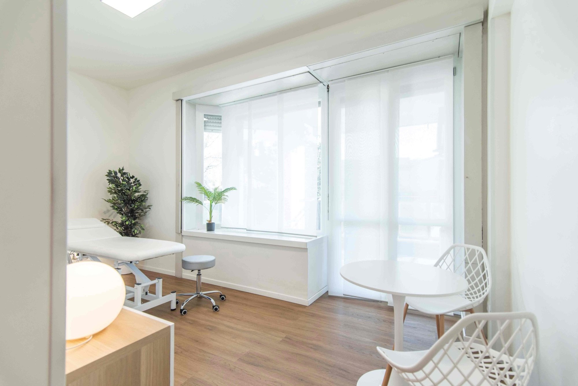 Lettino da visita vicino alla finestra con sedia bianca in studio professionale Premium presso Spatium Porta Romana, Milano