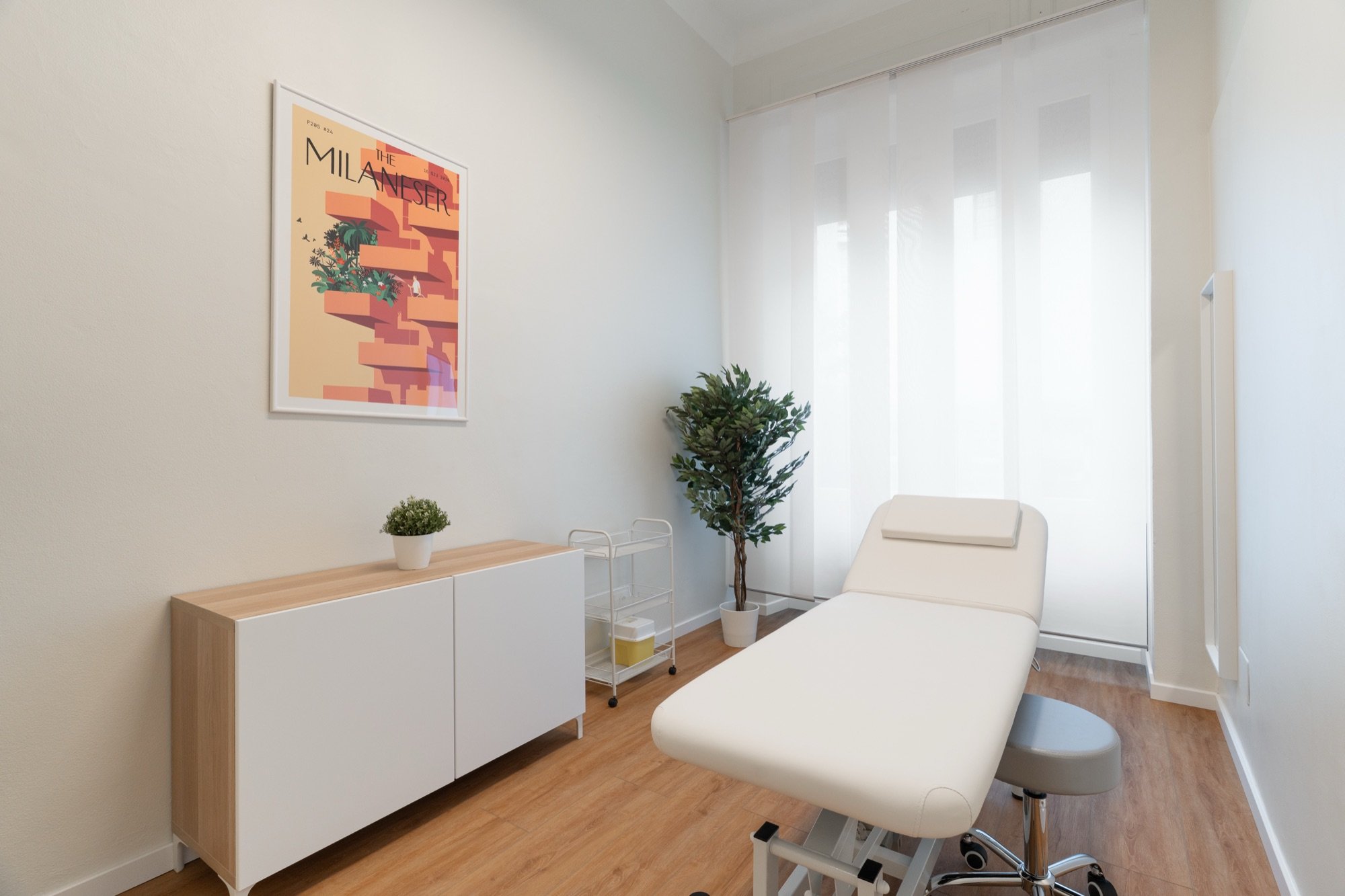 Lettino da visita con grande pianta e mobile in legno in studio professionale Premium presso Spatium Corso Vercelli, Milano
