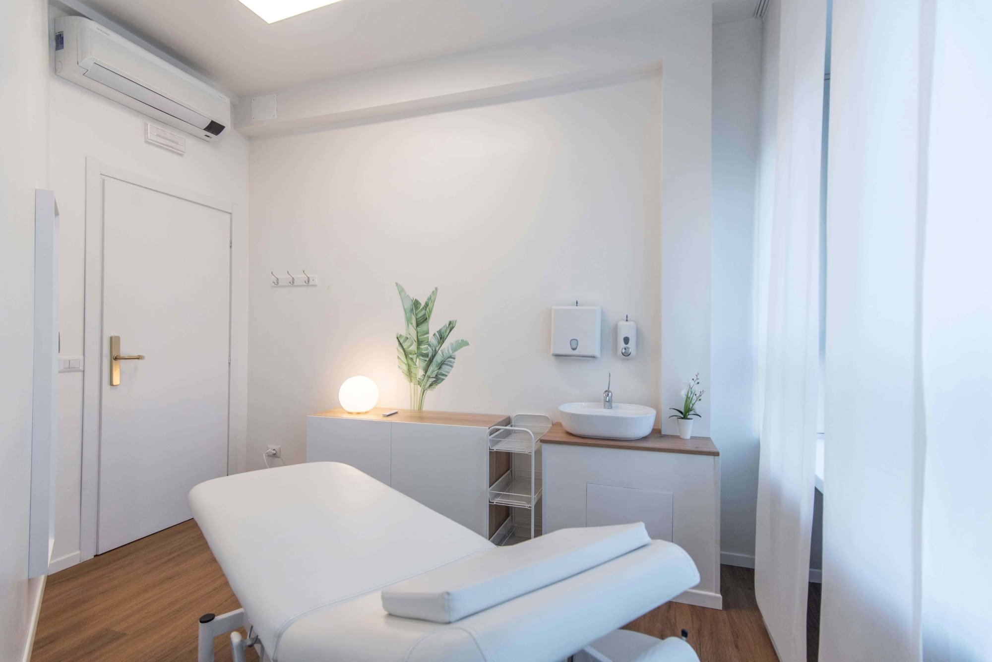 Lettino da visita in primo piano con lavabo e pianta in studio professionale Standard presso Spatium Porta Romana, Milano