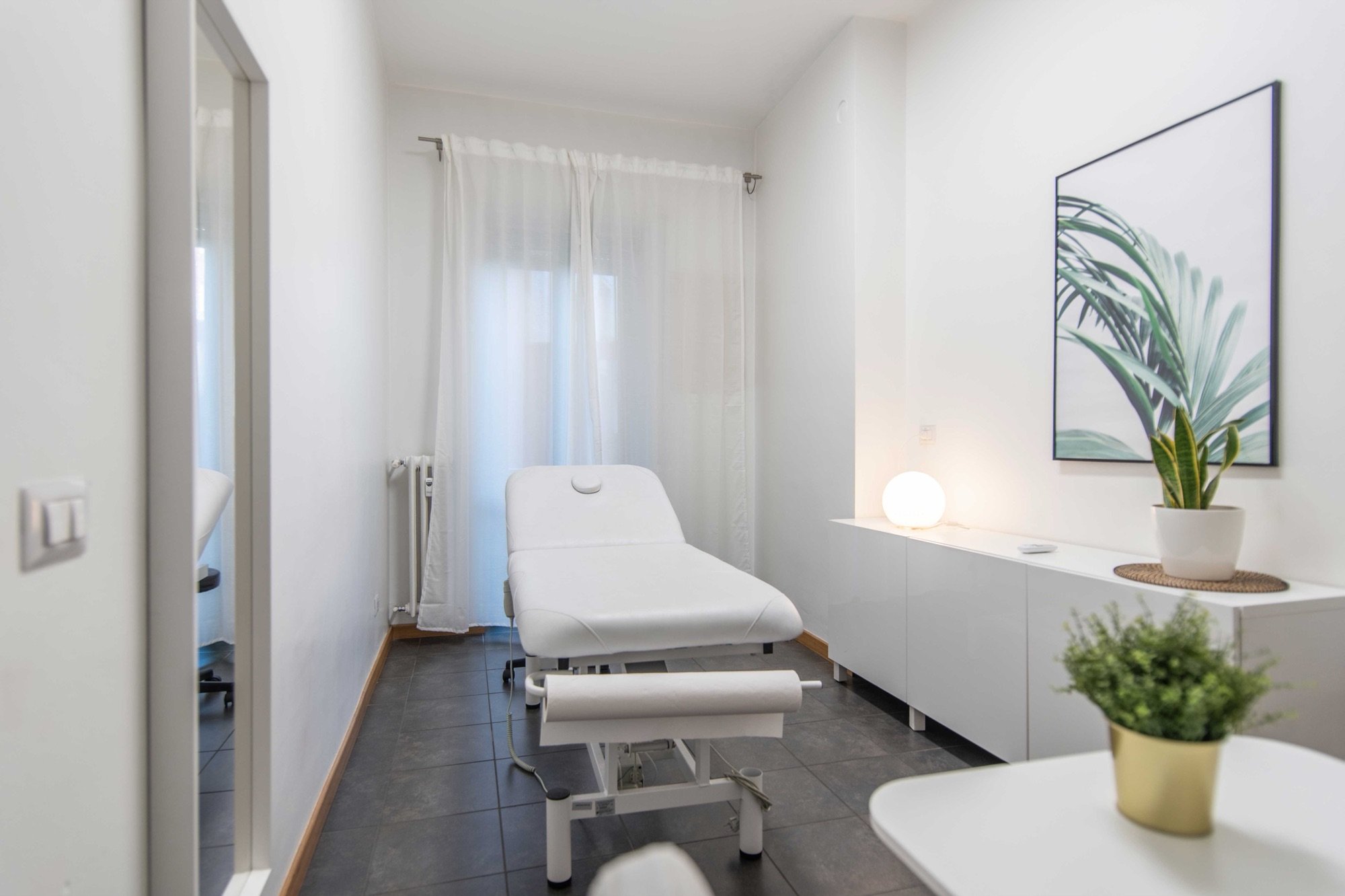 Lettino da visita con mobile, lampada e pianta in studio professionale Top presso Spatium Loreto, Milano