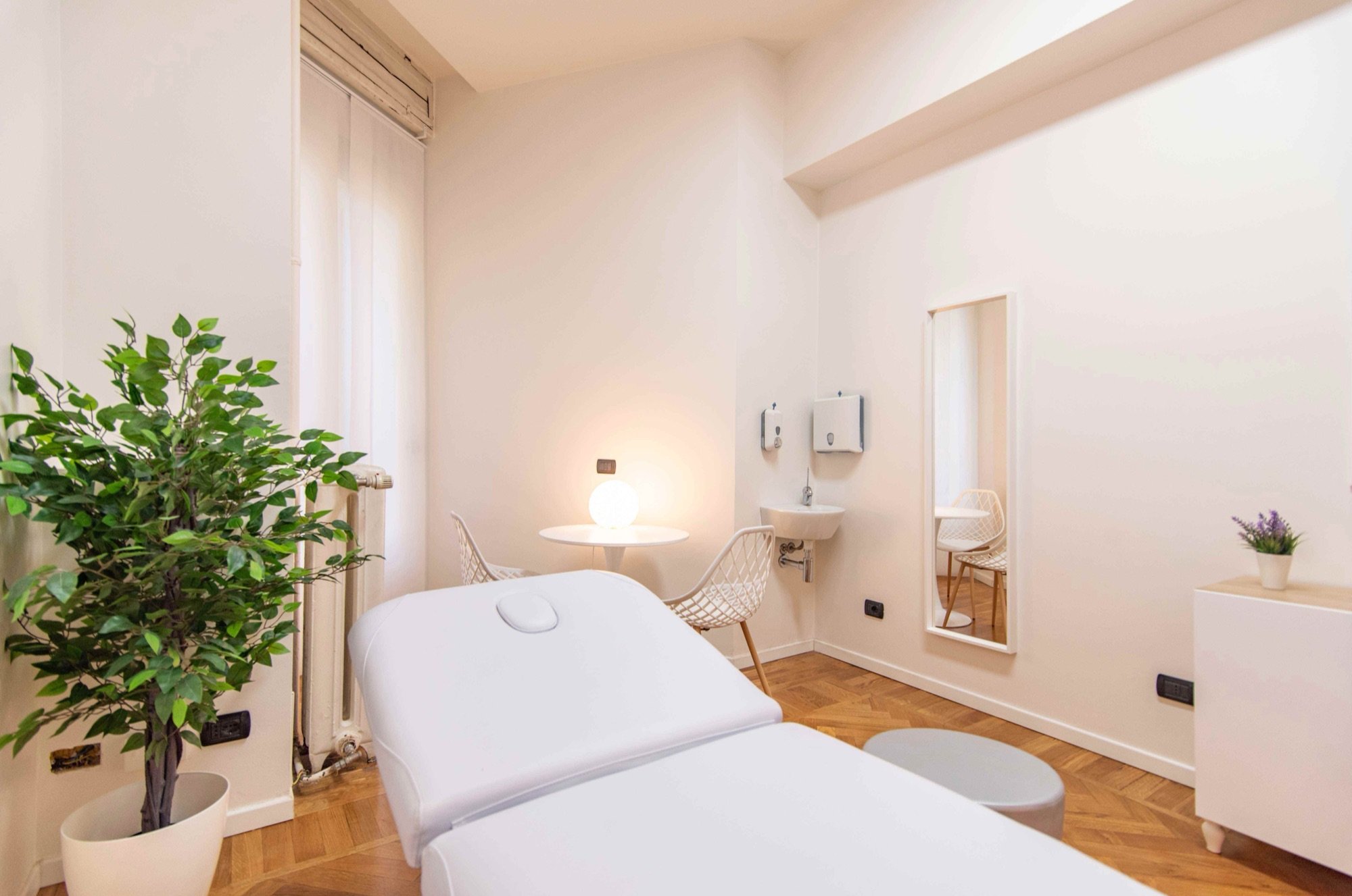Lettino da visita in primo piano con pianta e lavabo in studio professionale Premium presso Spatium Cinque Giornate, Milano