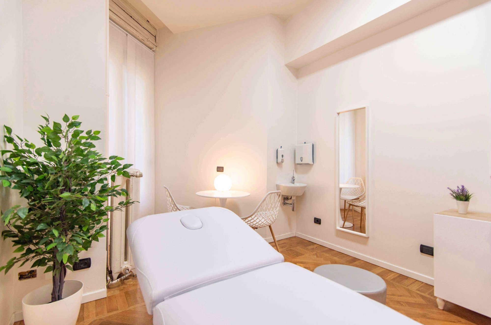 Lettino da visita in primo piano con pianta e lavabo in studio professionale Premium presso Spatium Cinque Giornate, Milano