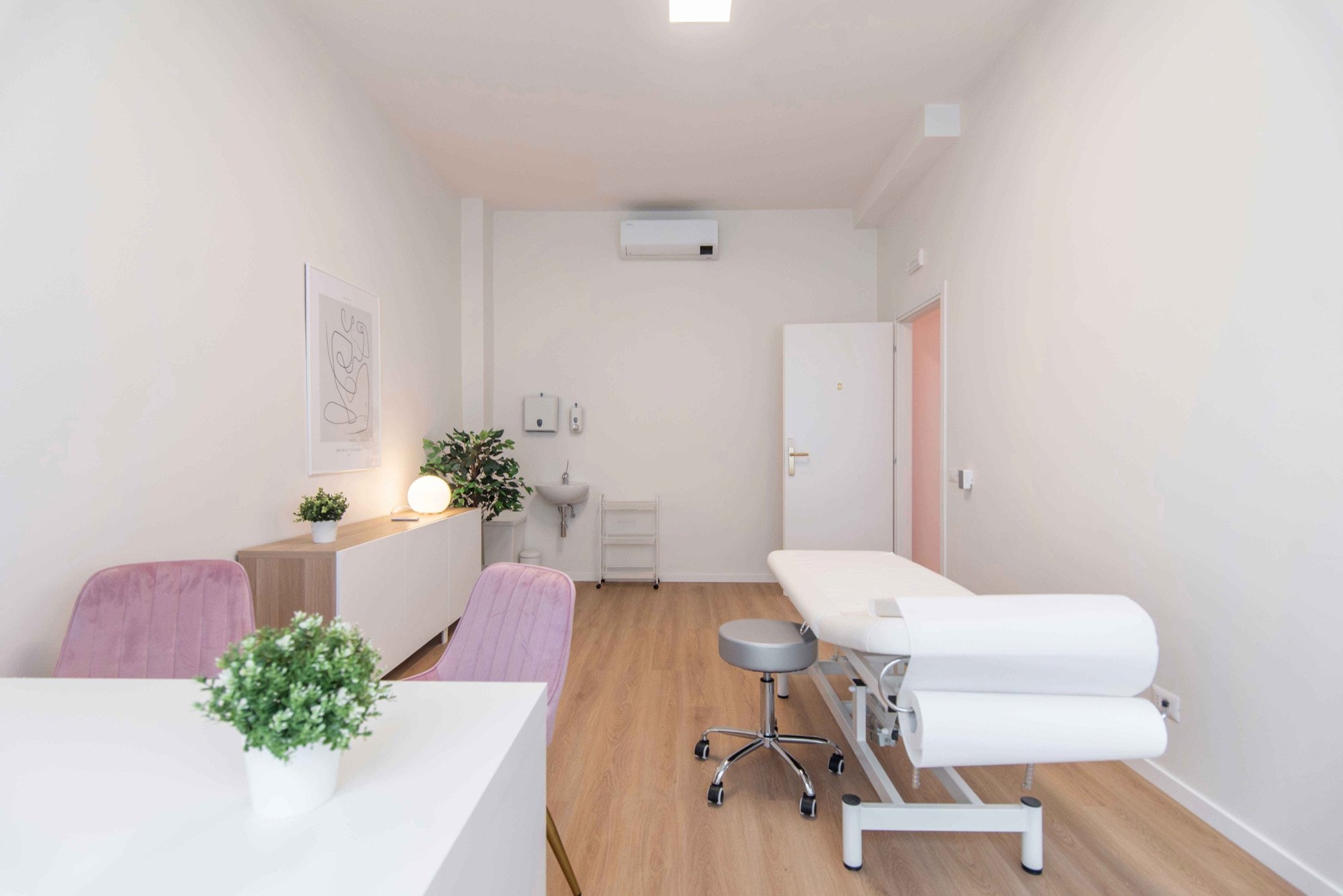 Lettino da visita con poltroncine rosa e mobile illuminato in studio professionale Lounge presso Spatium Vittor Pisani, Milano
