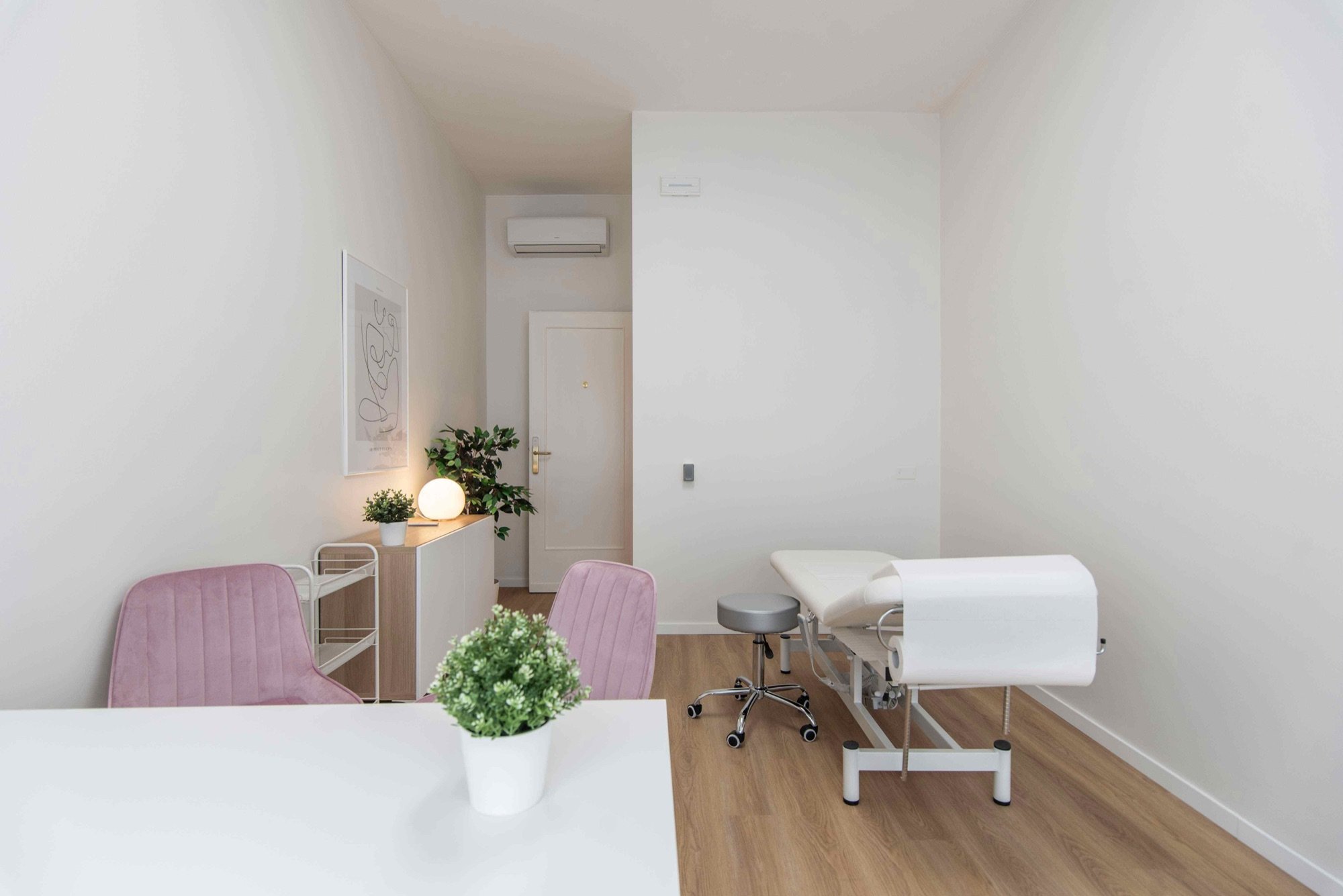 Lettino da visita con poltroncine rosa e mobile illuminato in studio professionale Exclusive presso Spatium Vittor Pisani, Milano