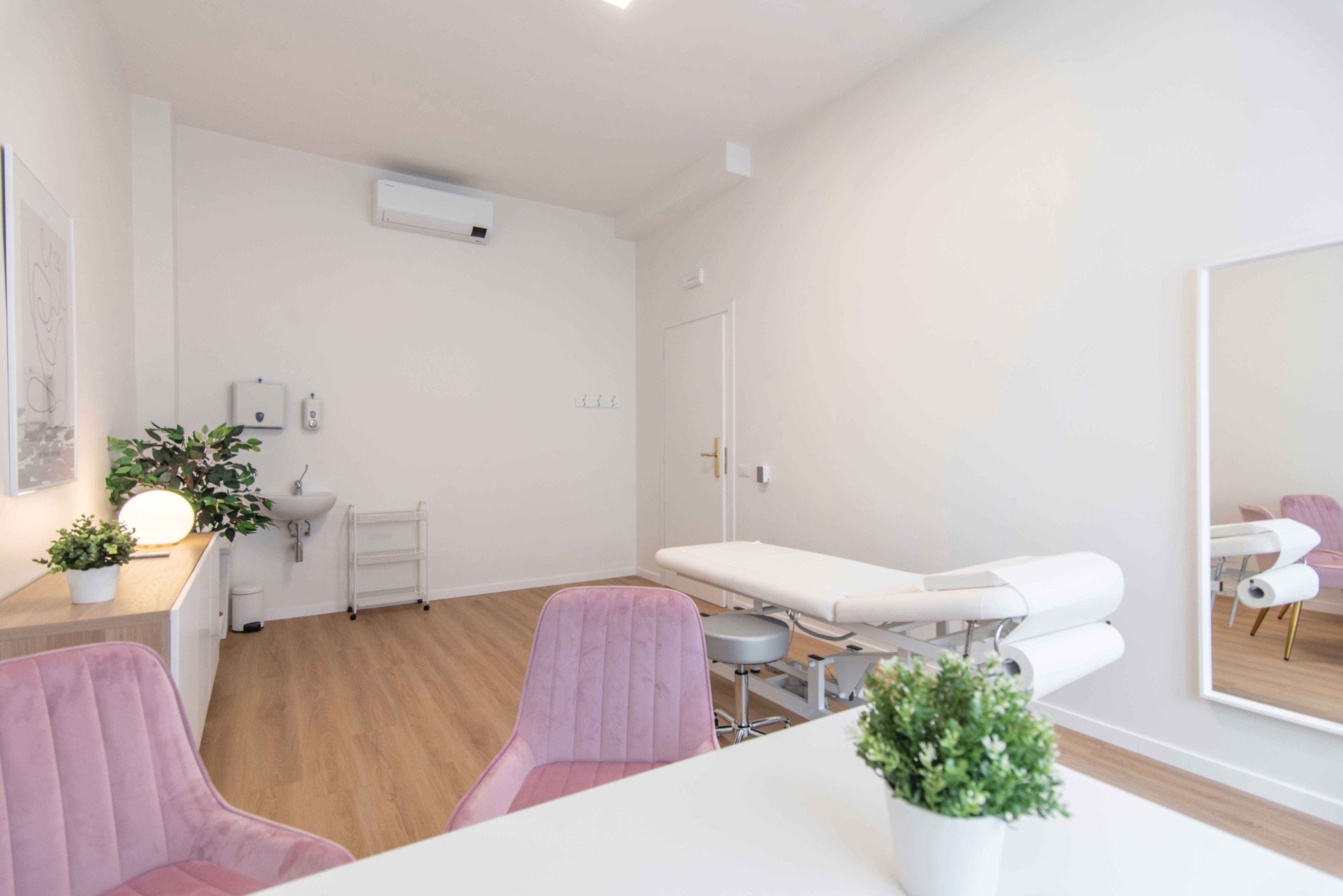 Lettino da visita con poltroncine rosa e tavolo in primo piano in studio professionale Lounge presso Spatium Vittor Pisani, Milano