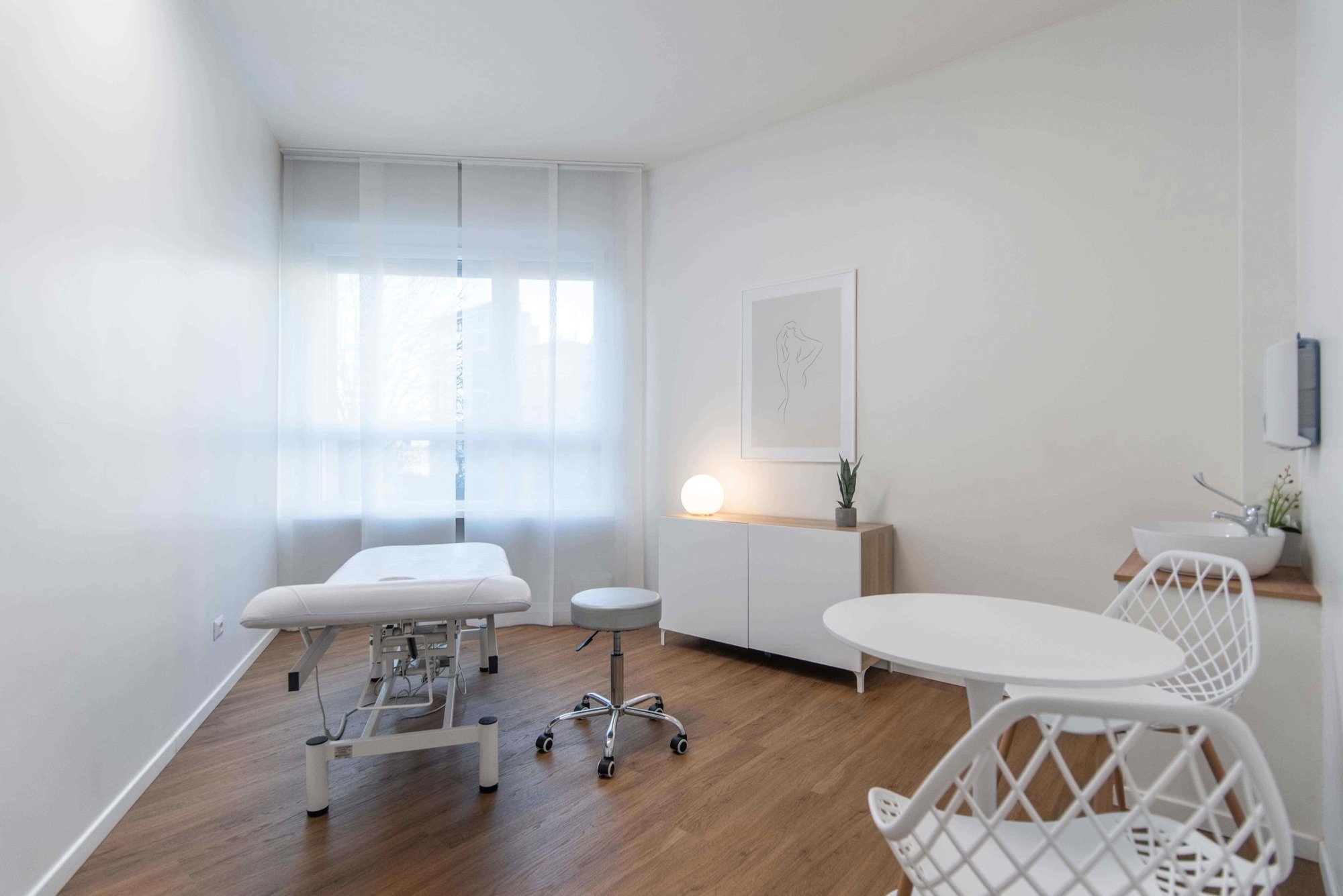 Lettino da visita con tavolino rotondo e sedia bianca in studio professionale Premium presso Spatium Porta Romana, Milano