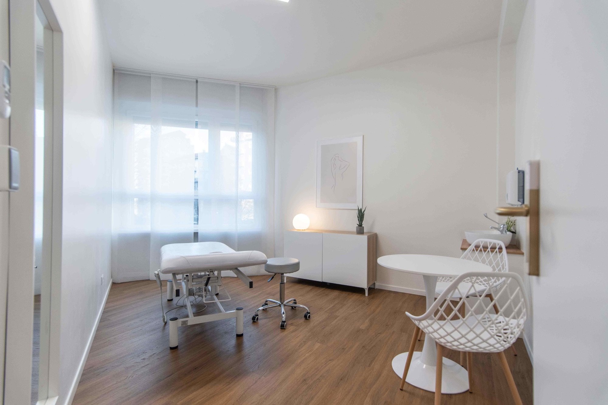 Lettino da visita con tavolino rotondo e sedie bianche in studio professionale Premium presso Spatium Porta Romana, Milano