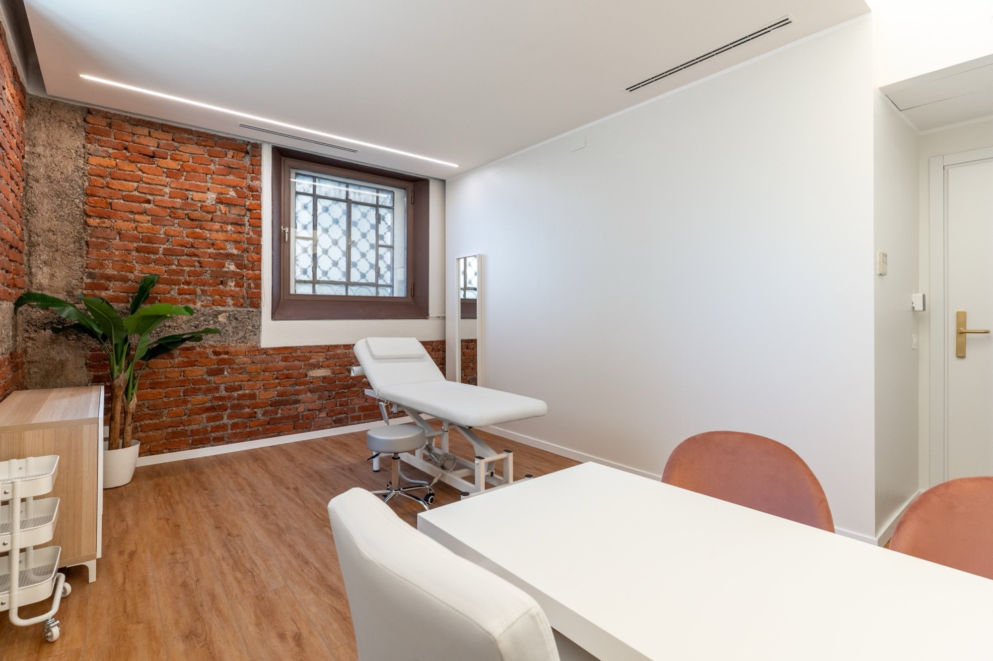 Lettino da visita con tavolo colloquio, poltroncina e parete in mattoni a vista in studio professionale Exclusive Spatium Corso Vercelli, Milano