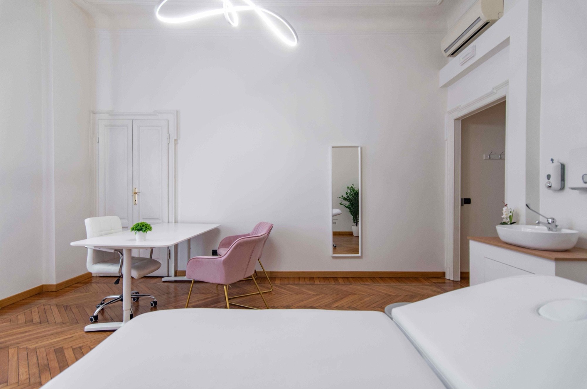 Lettino da visita in primo piano, tavolo e lavabo in studio professionale Lounge presso Spatium Cinque Giornate, Milano