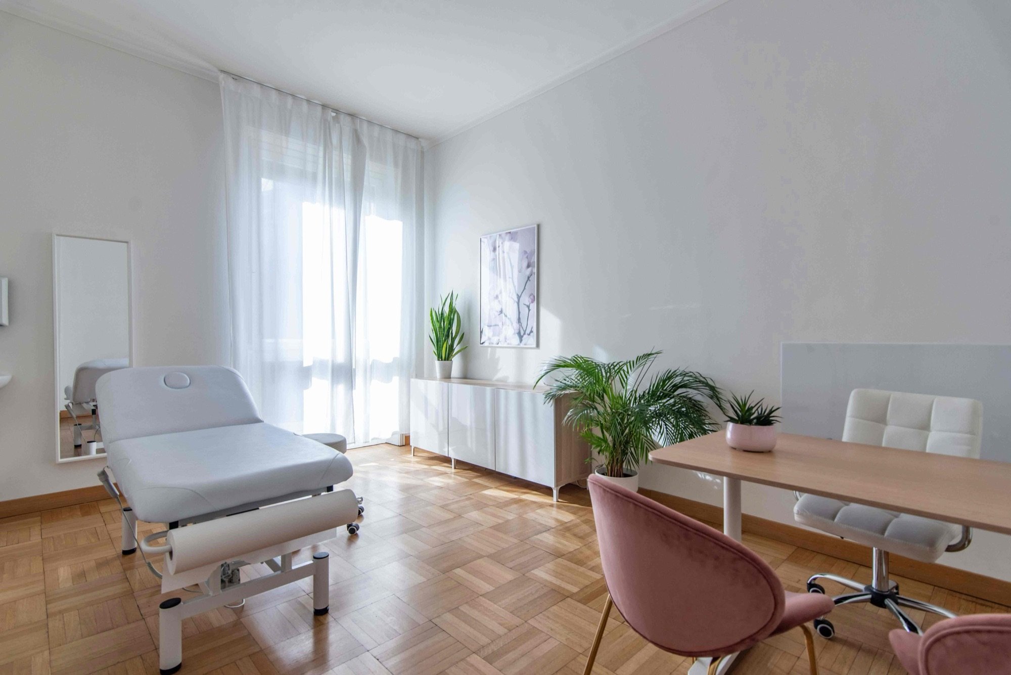 Lettino da visita in primo piano con tavolo e piante in studio professionale Exclusive presso Spatium Missori, Milano