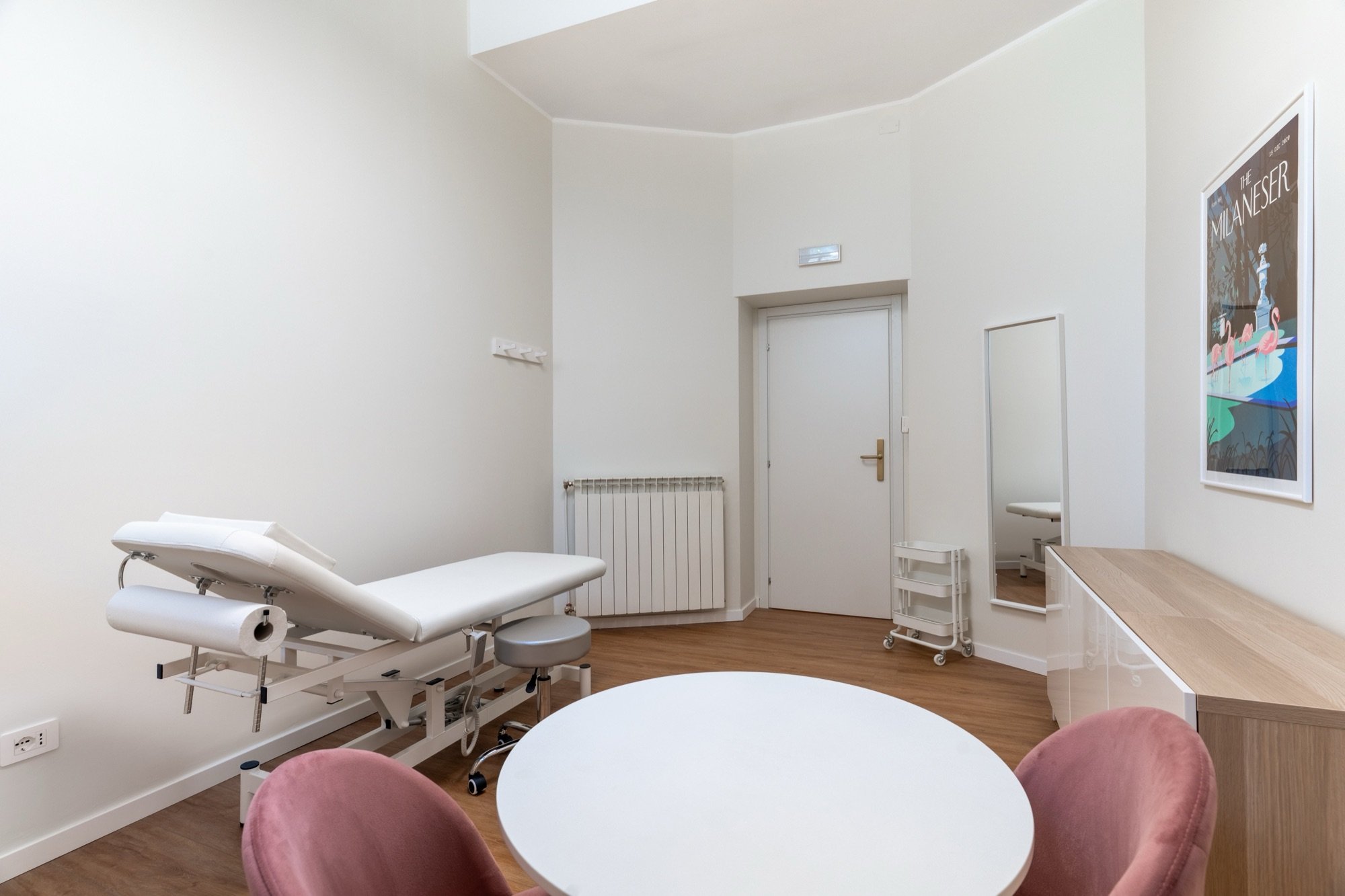 Lettino da visita sullo sfondo con tavolo rotondo e poltroncine in primo piano in studio professionale Premium Spatium Corso Vercelli, Milano