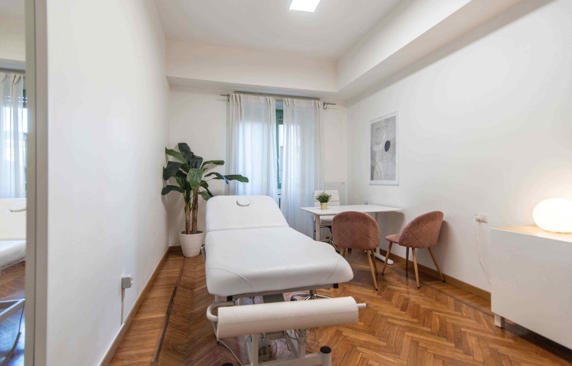 Lettino da visita con tavolo e sedute vicino alla finestra in studio professionale Exclusive presso Spatium Loreto, Milano