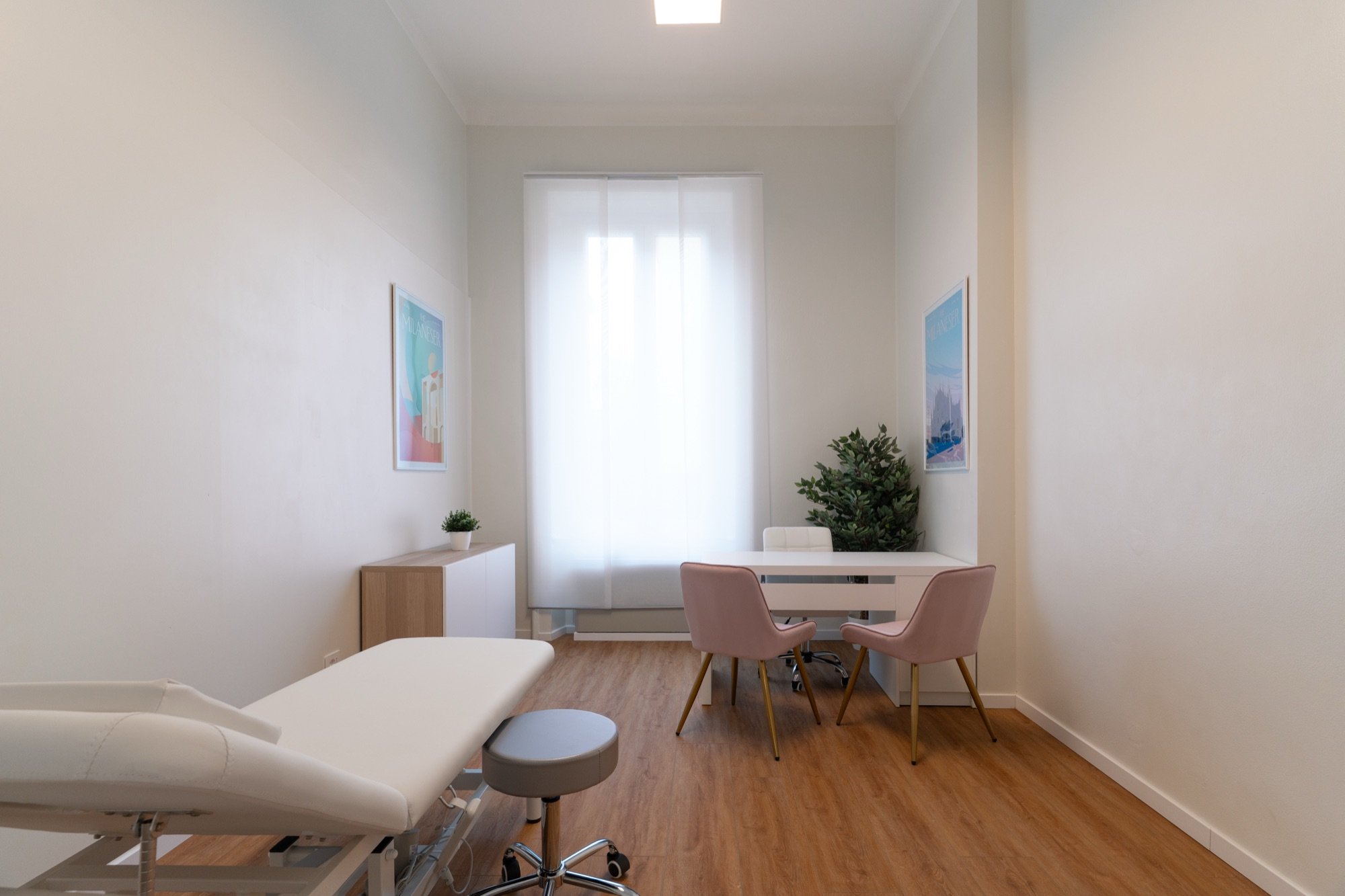 Lettino da visita in primo piano con tavolo e sedute rosa in studio professionale Exclusive presso Spatium Corso Vercelli, Milano