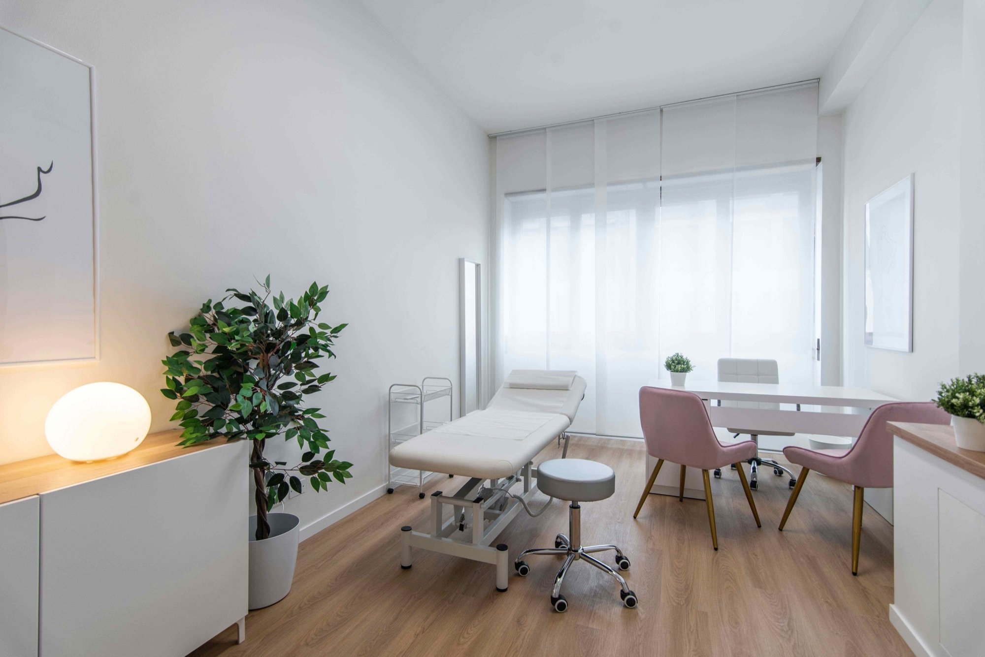 Lettino da visita con tavolo, sedute rosa e grande pianta in studio professionale Exclusive presso Spatium Vittor Pisani, Milano