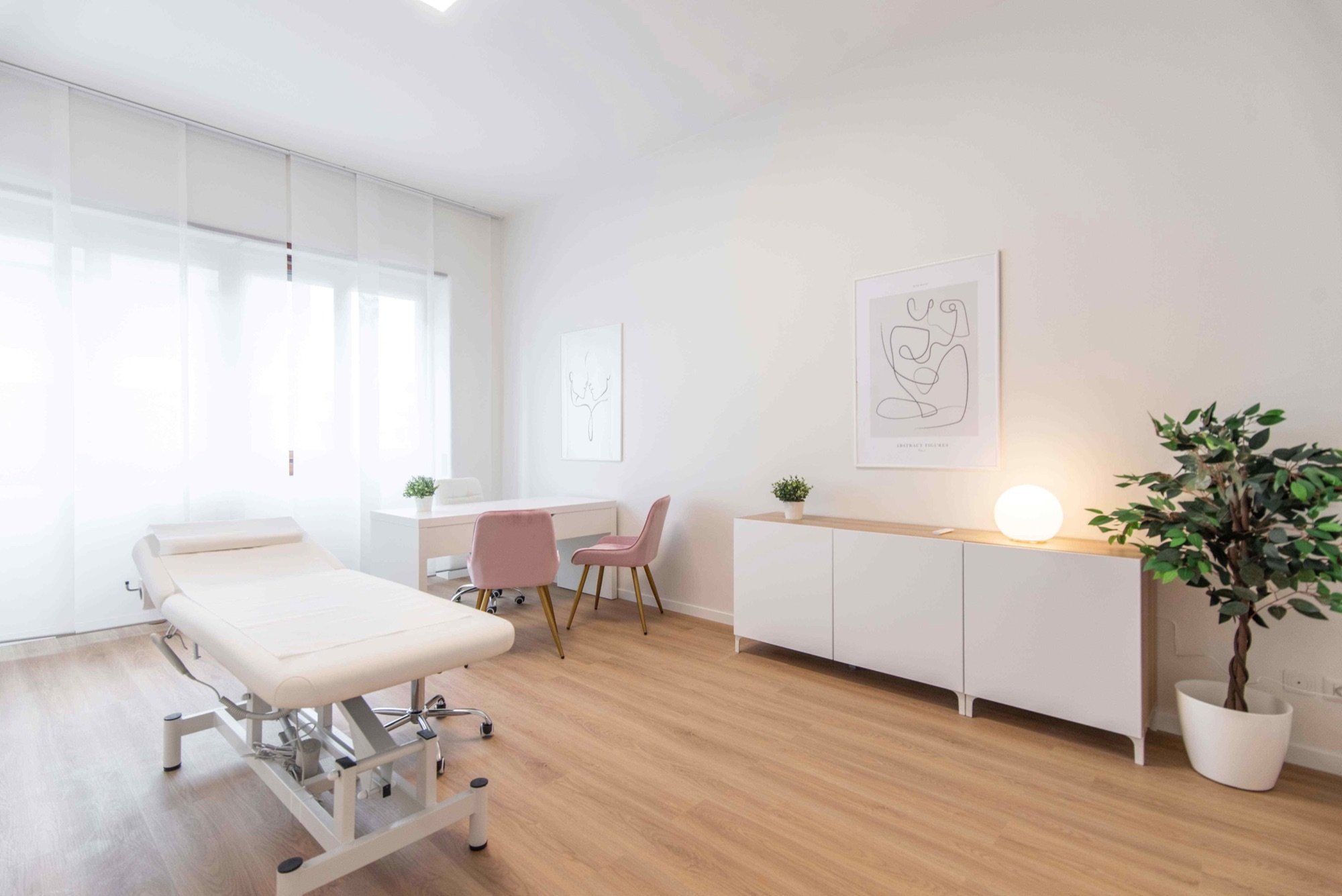 Lettino da visita con tavolo, sedute rosa e pianta in studio professionale Lounge presso Spatium Vittor Pisani, Milano