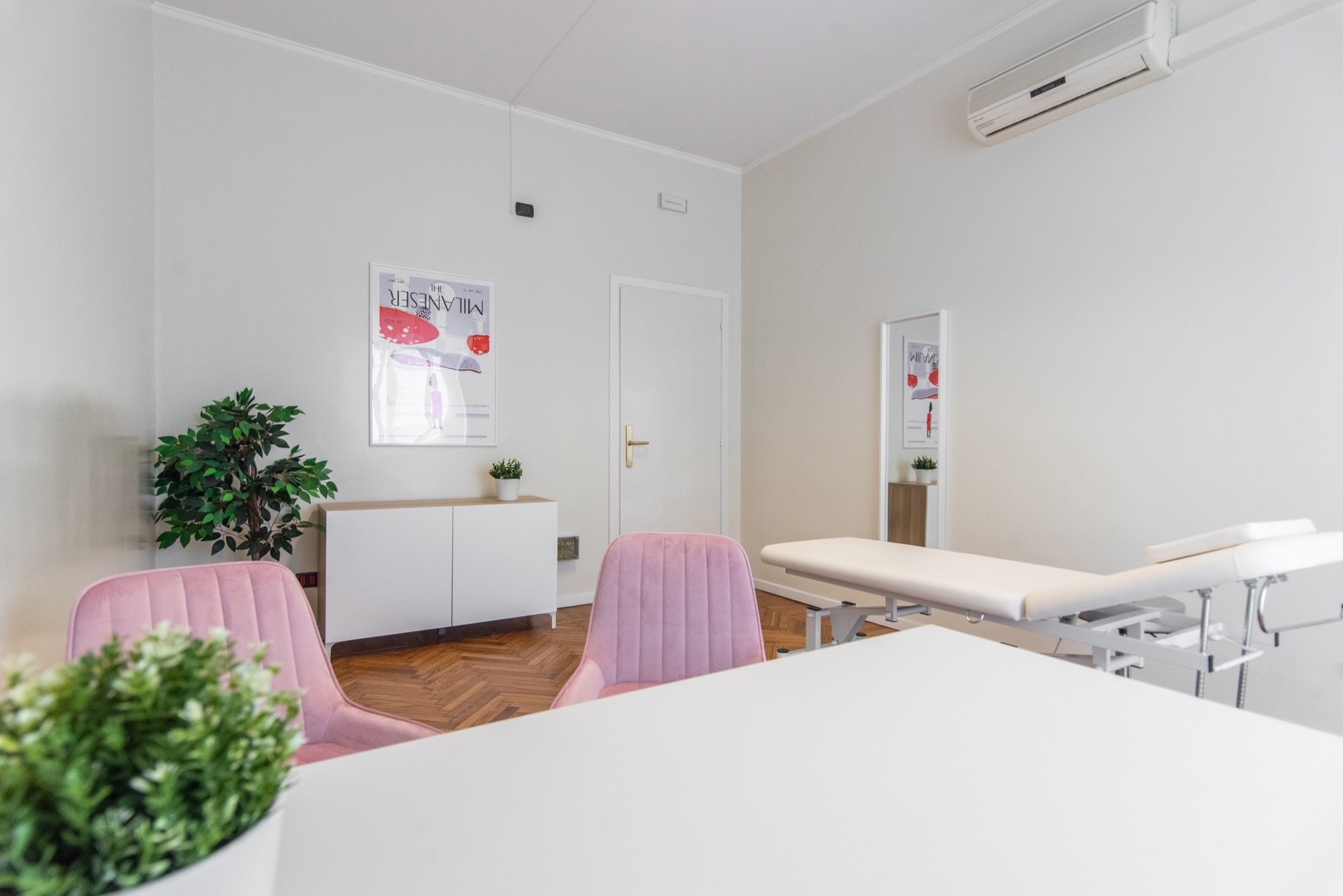 Scrivania in primo piano con poltroncine rosa e lettino in studio professionale Exclusive presso Spatium Santa Sofia, Milano