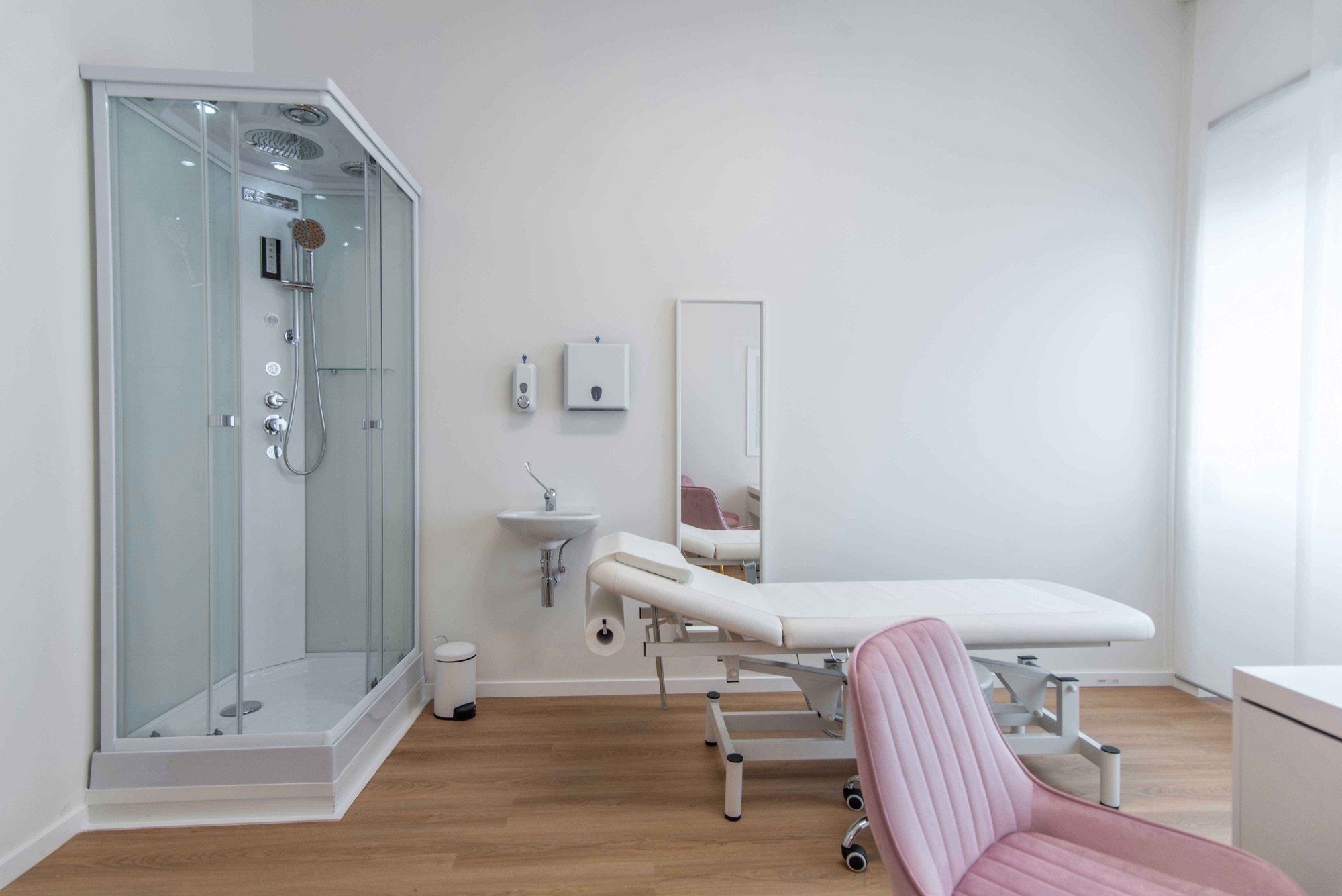 Vista dello studio con doccia, lettino e poltroncine rosa in studio professionale Top presso Spatium Vittor Pisani, Milano