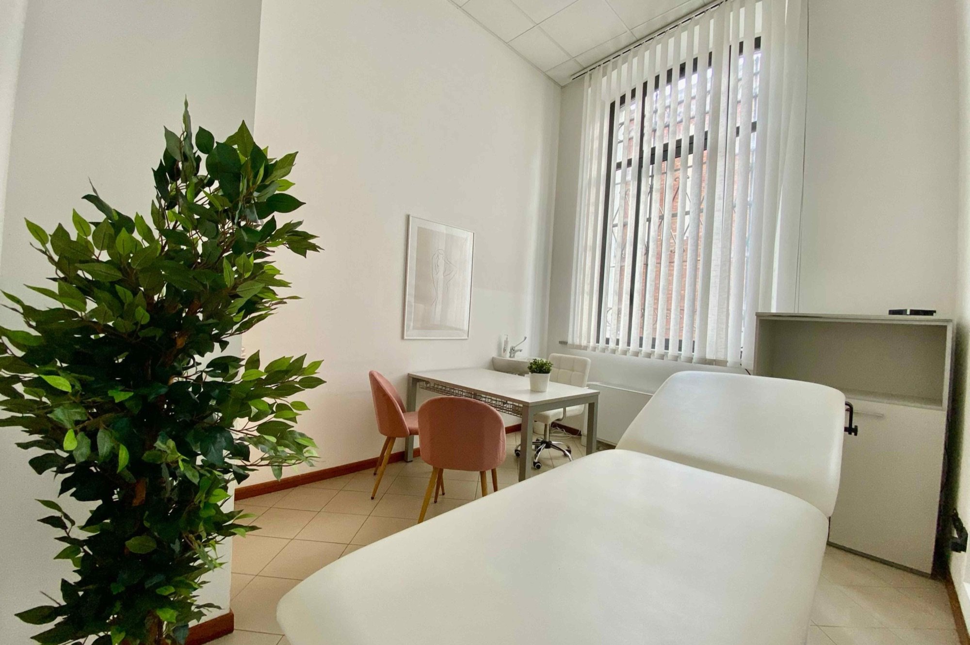 Lettino da visita con grande pianta e tavolo sullo sfondo in studio professionale presso Spatium San Giacomo, Vigevano